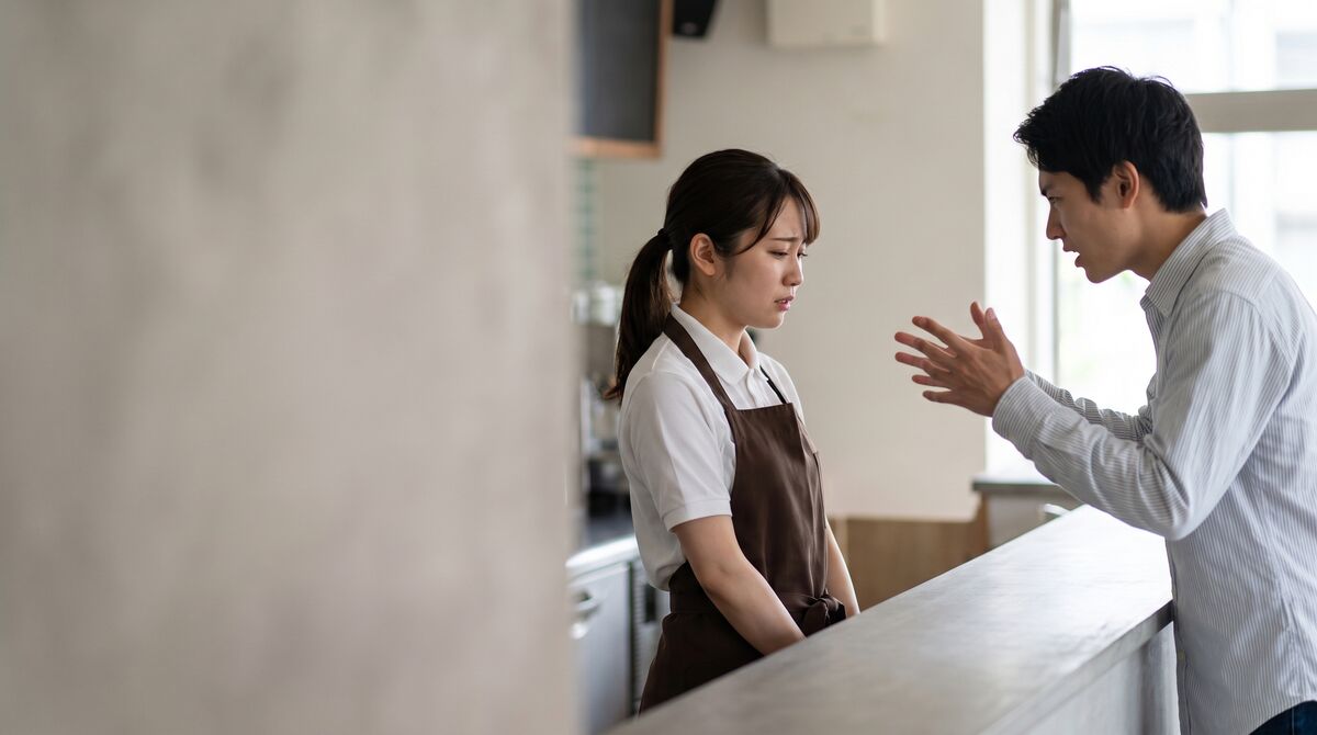 飲食店で女性店員に苦情を訴える男性客と冷静に対応する店員の写真